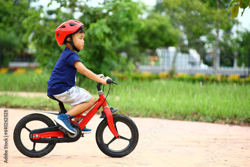 Asian Little boy riding a red bicycle in park