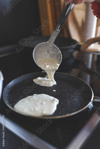 Ladle with dough for pancakes and a frying pan