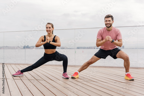 A couple of friends are using a fitness watch and a sports app.  A man and a woman train together. The trainer and the client teach fitness exercises. Confident  strong people in sportswear.