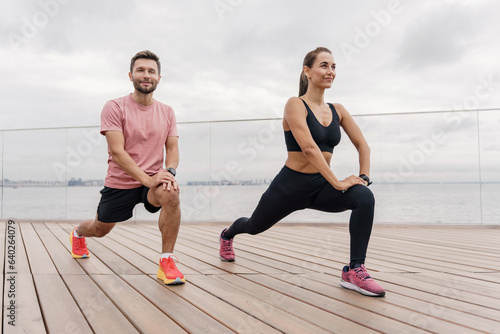 A personal trainer and a client teach fitness exercises. Confident, strong people in sportswear. A couple of friends' instructors enjoy a fitness watch and a sports app.  