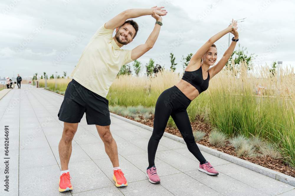 Obraz premium A man and a woman training together. Friends outdoor exercise physical activity for the body. People in fitness clothes and sneakers are doing sports. Use a fitness watch.