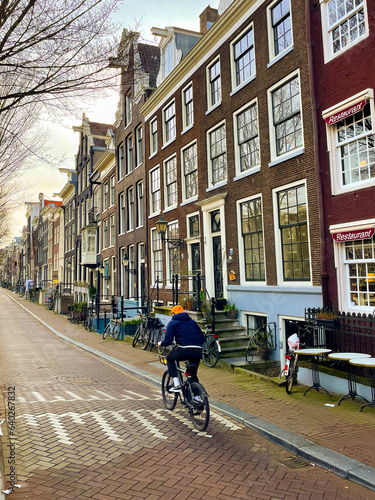 Unrecognizable man riding a bike down a street in Amsterdam's historic city center.