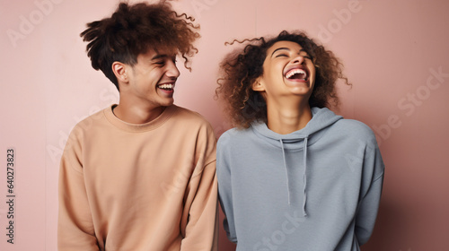 Funny best friends laughing cheerfully while standing together in a studio
