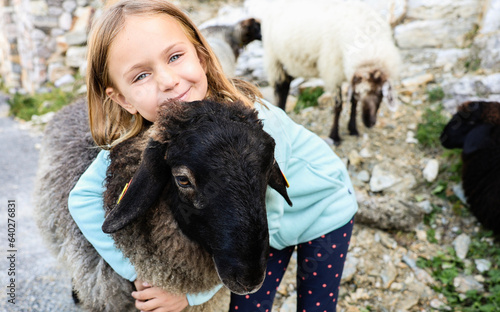 happy smiling child girl hugging sheep at farm, children love play animal, kid on nature, positive emotions, travel in Switzerland biopark, swiss sheep simbol, toddler face