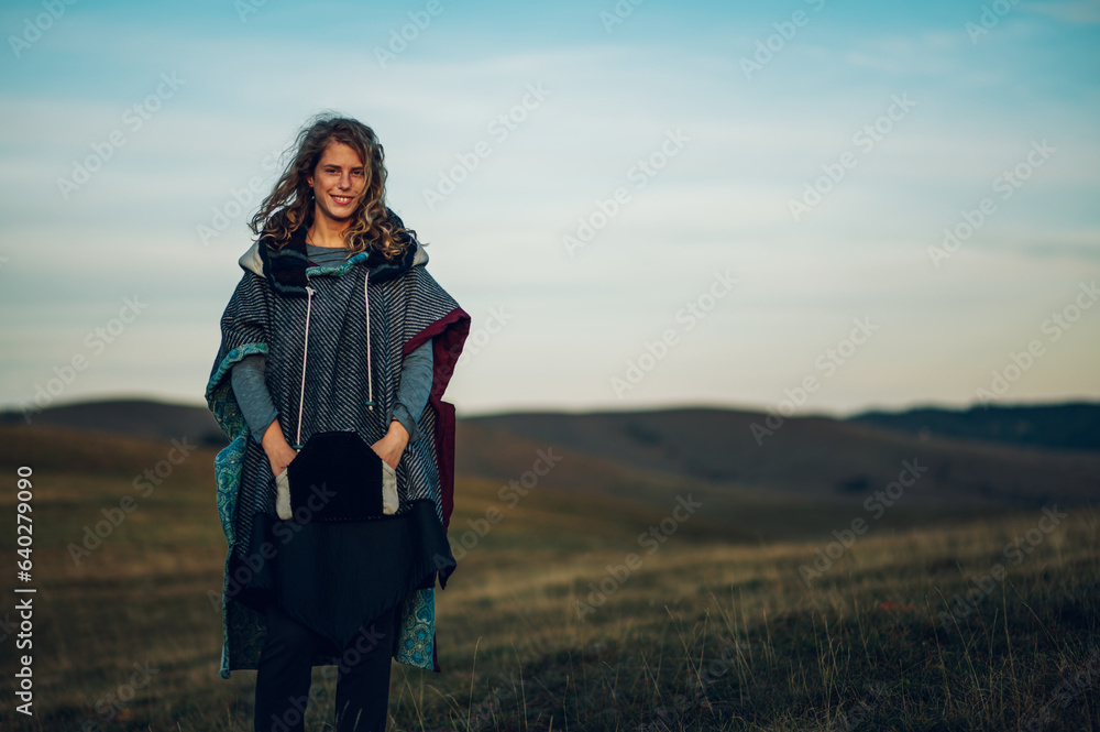 Portrait of a stylish woman hiking on a mountain path with tall grass