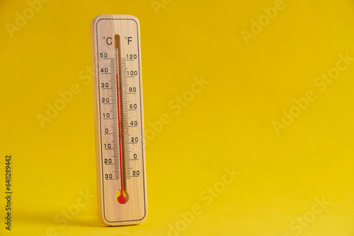 Wooden outdoor thermometer yellow background. photo