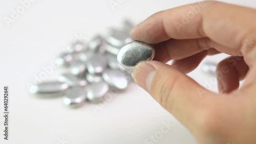 Man's hand holding a lump of silver or platinum or a rare earth mineral on white background