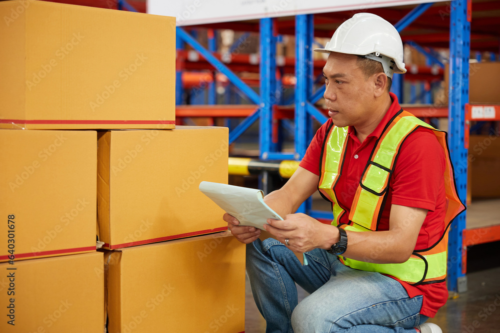 Fototapeta premium factory worker or warehouser checking corrugated boxes in the warehouse storage