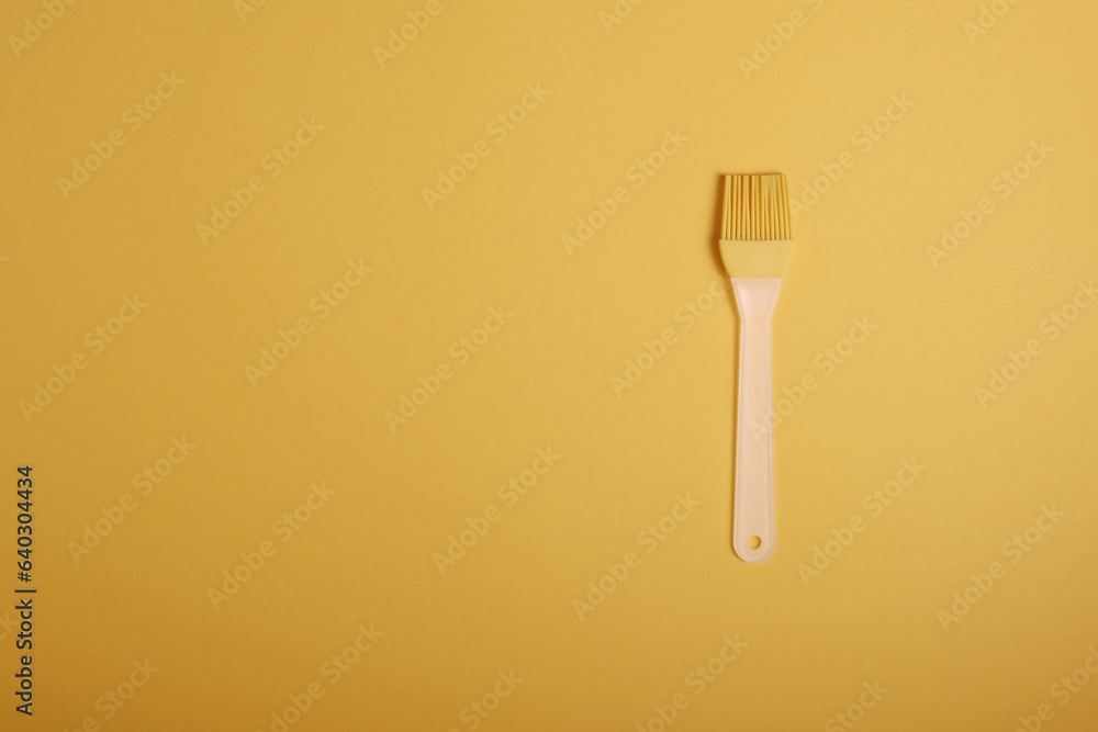 A culinary yellow silicone brush with a light handle, on a harmonious sunny background. Accessories for kitchen and baking. Copy space view A culinary yellow silicone brush with a light handle, on a harmonious sunny background. Accessories for kitchen and baking. Copy space view