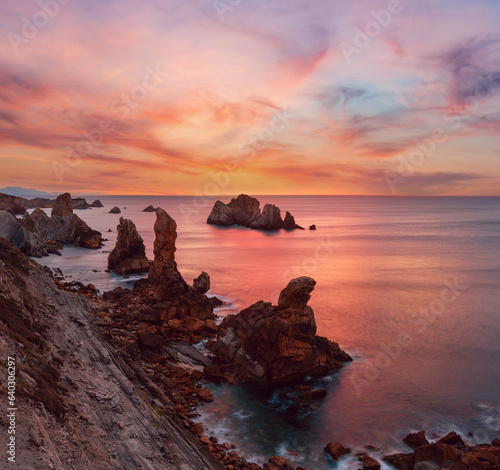 Arnia Beach sunset view with pink sky (Spain). Atlantic Ocean coastline.