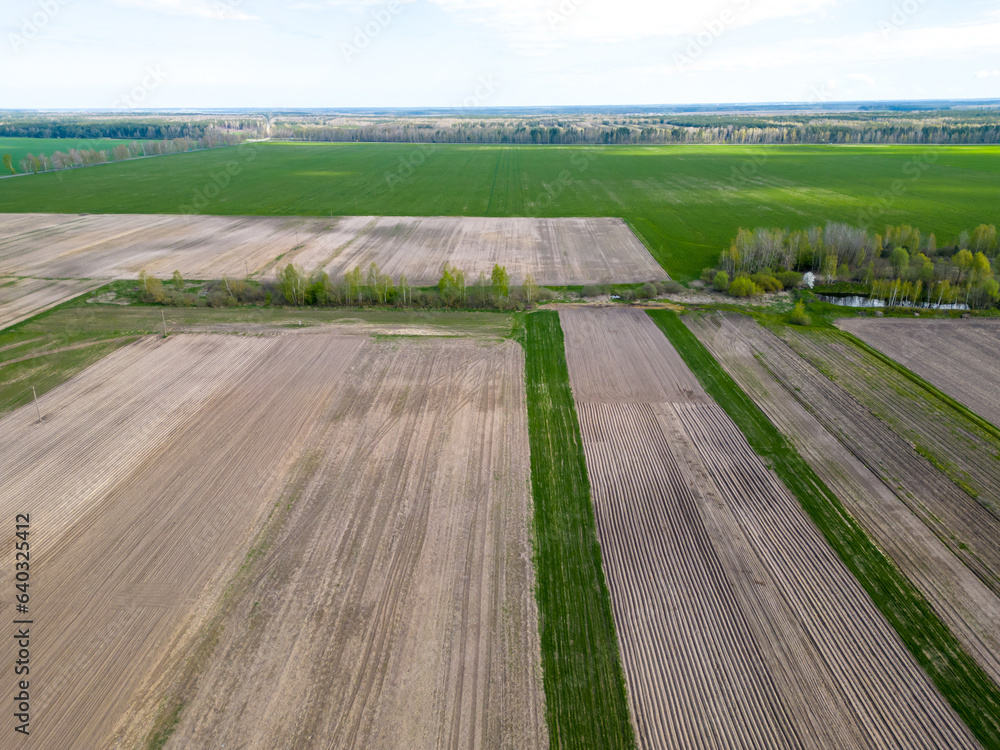 Drone photo of a plowed fields. Aerial view of a farmer's field. A top view of an agricultural field with different cereal crops that creates an abstract picture of multicolored straight lines.