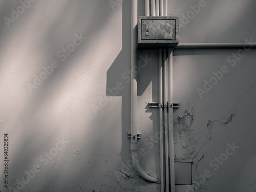 Close-up beautiful light electrical equipment box  steel pipe electric wire used for outdoor wiring Fire  Conduit Background cracked plaster wall texture. Transformer box and corrugated pip.
