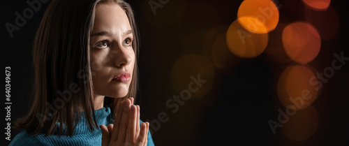 Praying young woman on dark...