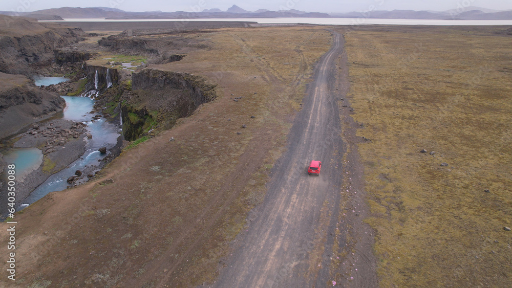 AERIAL - Jeep driving off-road terrain exploring Sigoldugljufur, a canyon in the Icelandic Highlands. A 4x4 jeep driving dirt road traveling in Iceland sightseeing wilderness. woman traveler waving. AERIAL - Jeep driving off-road terrain exploring Sigoldugljufur, a canyon in the Icelandic Highlands. A 4x4 jeep driving dirt road traveling in Iceland sightseeing wilderness. woman traveler waving.