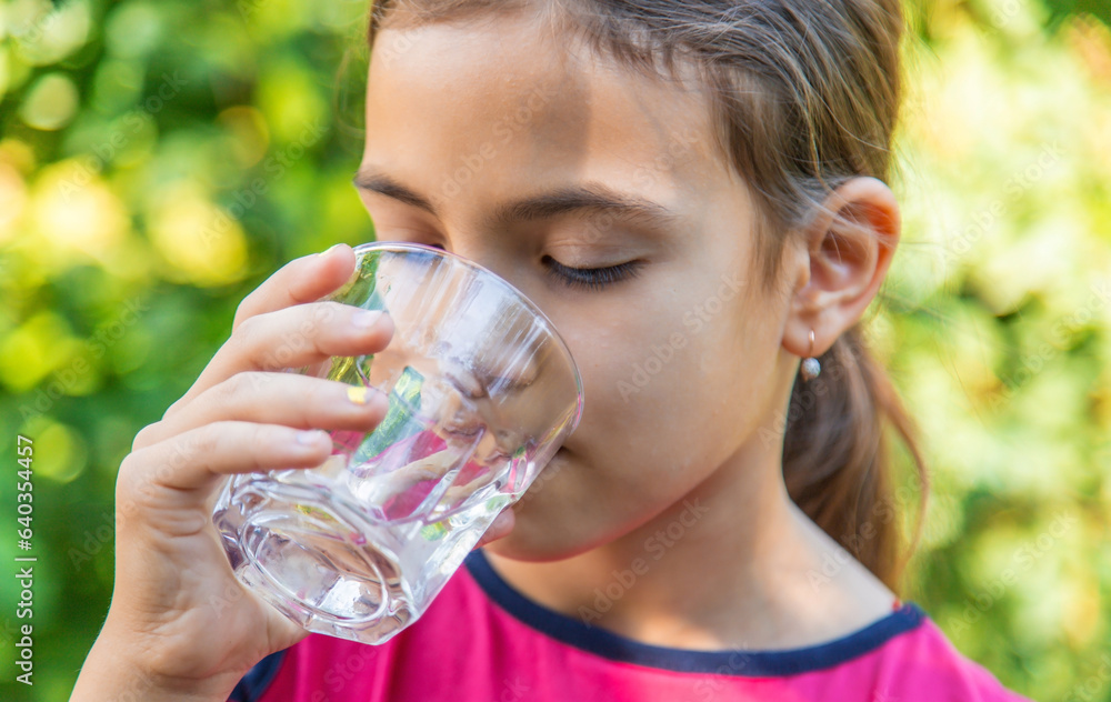 The child drinks water from a glass. Selective focus. The child drinks water from a glass. Selective focus.