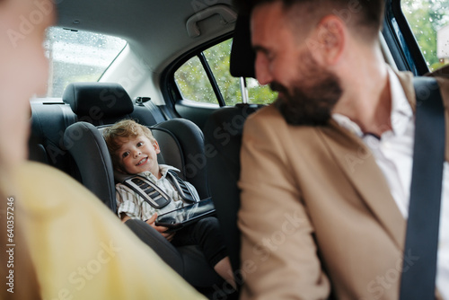 Cute little boy sitting in his car seat, playing on tablet. © Halfpoint