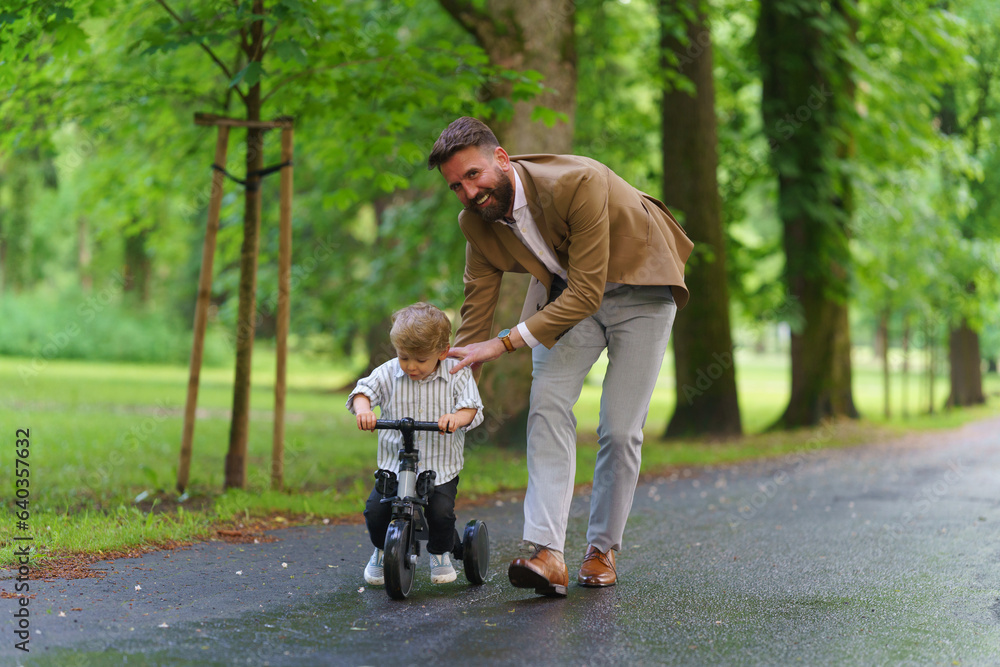 Single father teaching his little son how to bike in public park. Single father teaching his little son how to bike in public park.