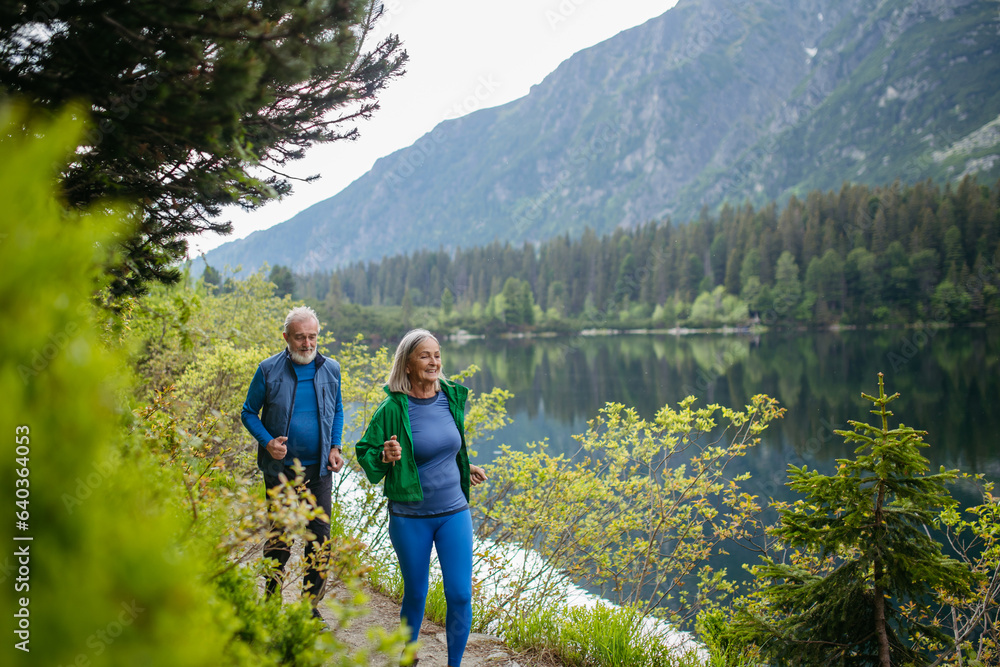 Senior couple running by the lake in the mountains.