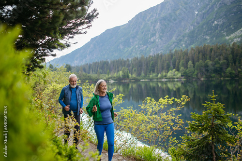 Senior couple running by the lake in the mountains.