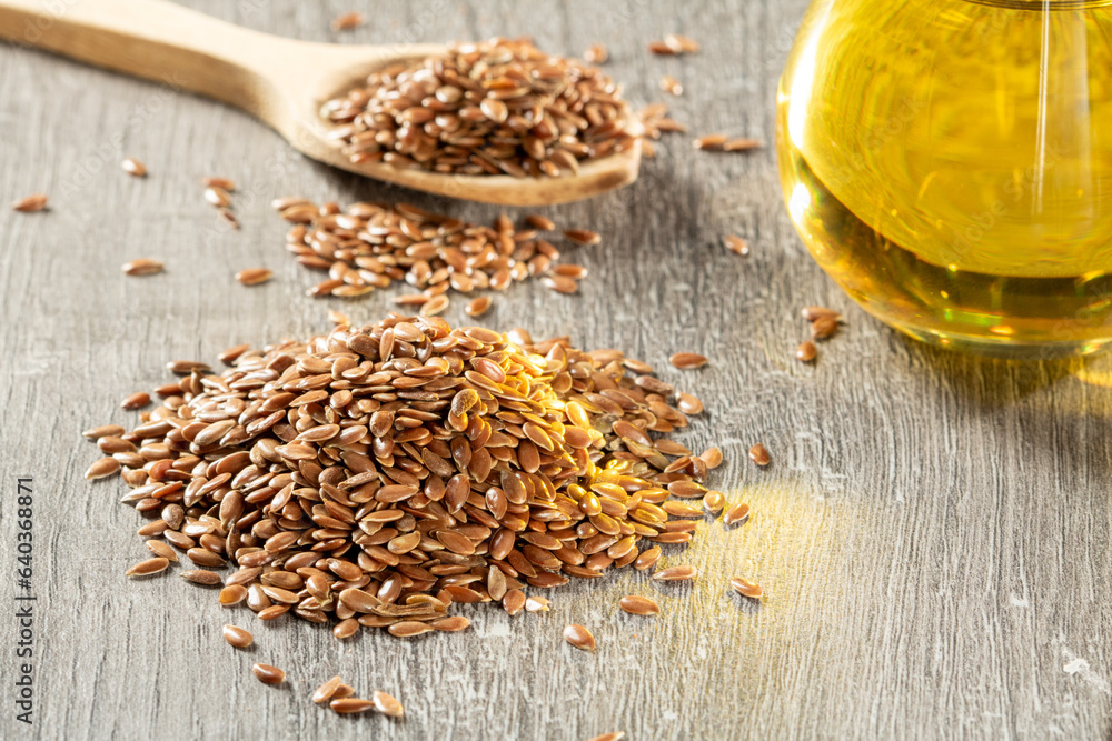 A bunch of flax seeds and a jar of linseed oil on a wooden table A bunch of flax seeds and a jar of linseed oil on a wooden table
