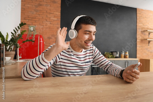 Young man in headphones usi...