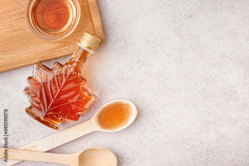Fotografía Bottle, bowl and spoons of tasty maple syrup on light background