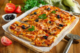 Fresh homemade rectangular pizza with ham, tomatoes and olives