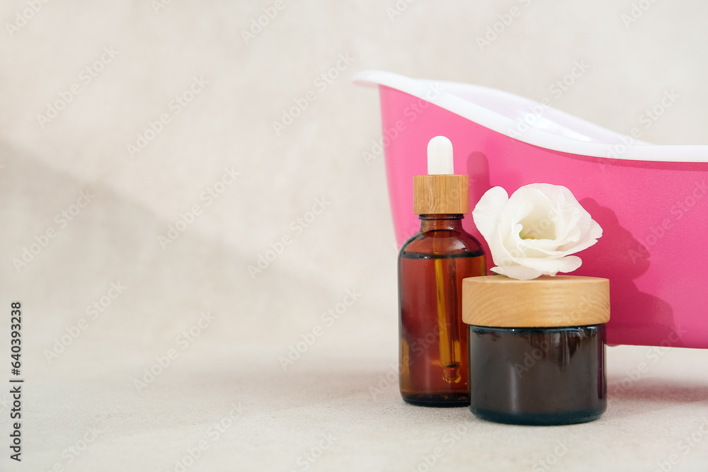 Small bathtub, cosmetic products and flower on light background Small bathtub, cosmetic products and flower on light background