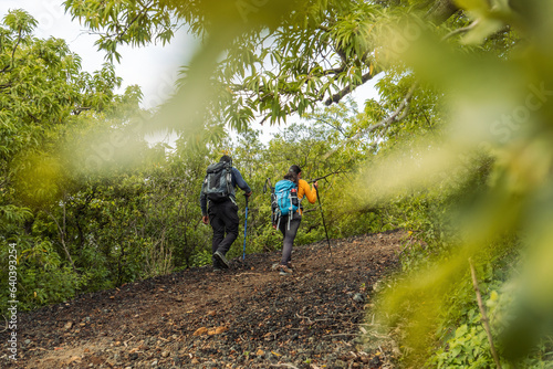Outdoor Adventure: Man with Black Backpack and Woman with Blue Backpack Exploring the Mountain