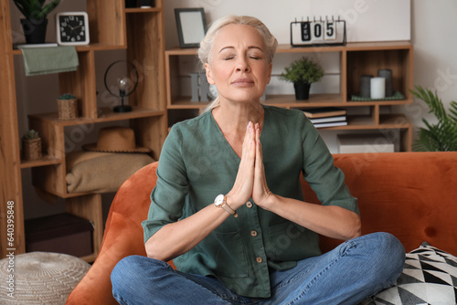 Mature woman meditating on ...