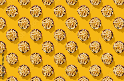 Pattern of pasta conchiglie noodle in wooden bowl on yellow pastel background