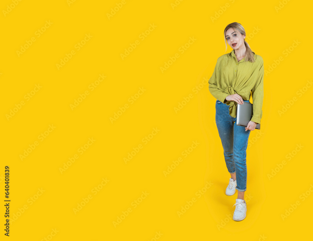 Holding closed laptop, full body view young happy blonde girl holding closed laptop. IT worker, student, employee woman wear denim, green shirt. carrying notebook pc computer looking camera. Holding closed laptop, full body view young happy blonde girl holding closed laptop. IT worker, student, employee woman wear denim, green shirt. carrying notebook pc computer looking camera.