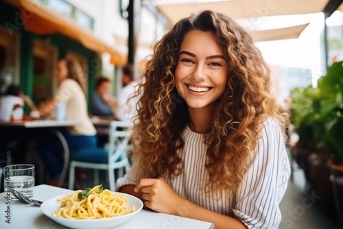 Girl eats pasta in street cafe