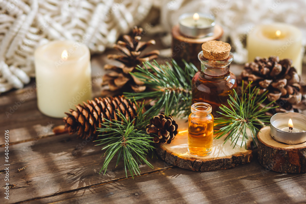 Assortment of natural christmas essential oils in small bottles. Candles, branches of fir tree. Aromatherapy, cozy home atmosphere, holiday festive mood. Close up macro, wooden background. Zero waste Assortment of natural christmas essential oils in small bottles. Candles, branches of fir tree. Aromatherapy, cozy home atmosphere, holiday festive mood. Close up macro, wooden background. Zero waste
