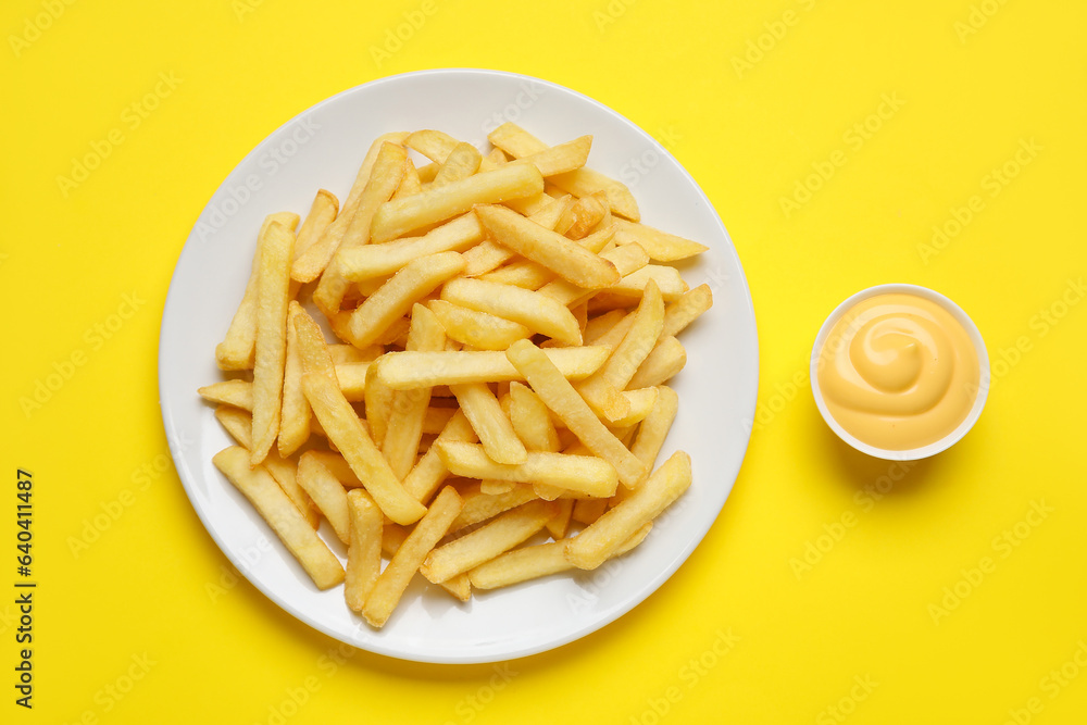 Plate with golden french fries and cheese sauce on yellow background Plate with golden french fries and cheese sauce on yellow background