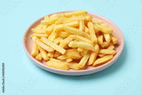 Plate with golden french fries on blue background