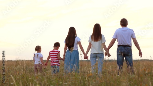 Large family with children raise up joined hands showing happiness at farmland