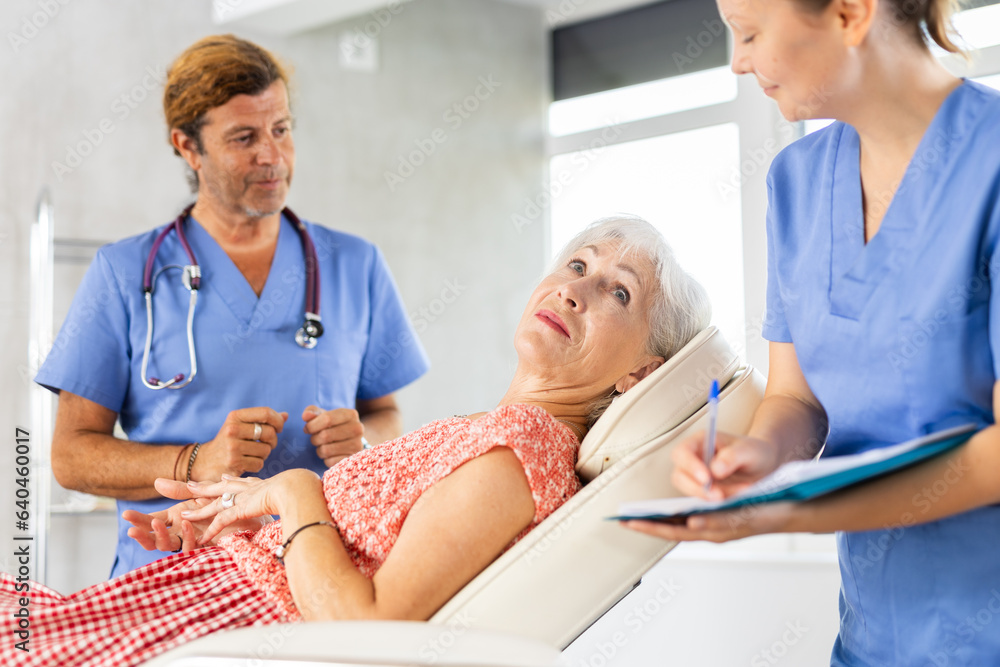 Obraz premium Professional physician consulting woman patient in clinic. Nurse filling form at consultation.