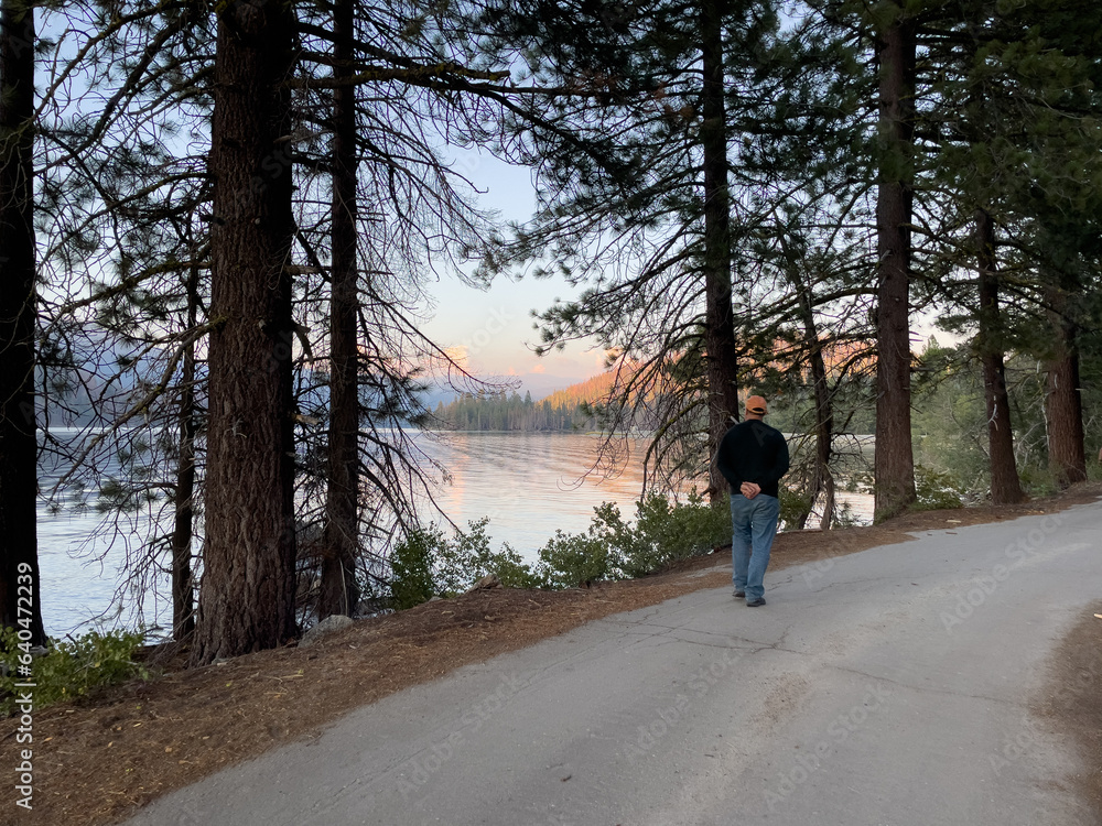 One man walking with hands behind his back on a single lane road next