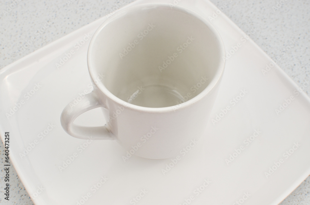 Closeup of an empty high quality china cup on a white plate, a perfect match.