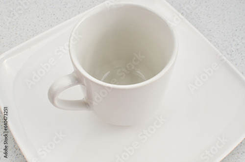 Closeup of an empty high quality china cup on a white plate  a perfect match.