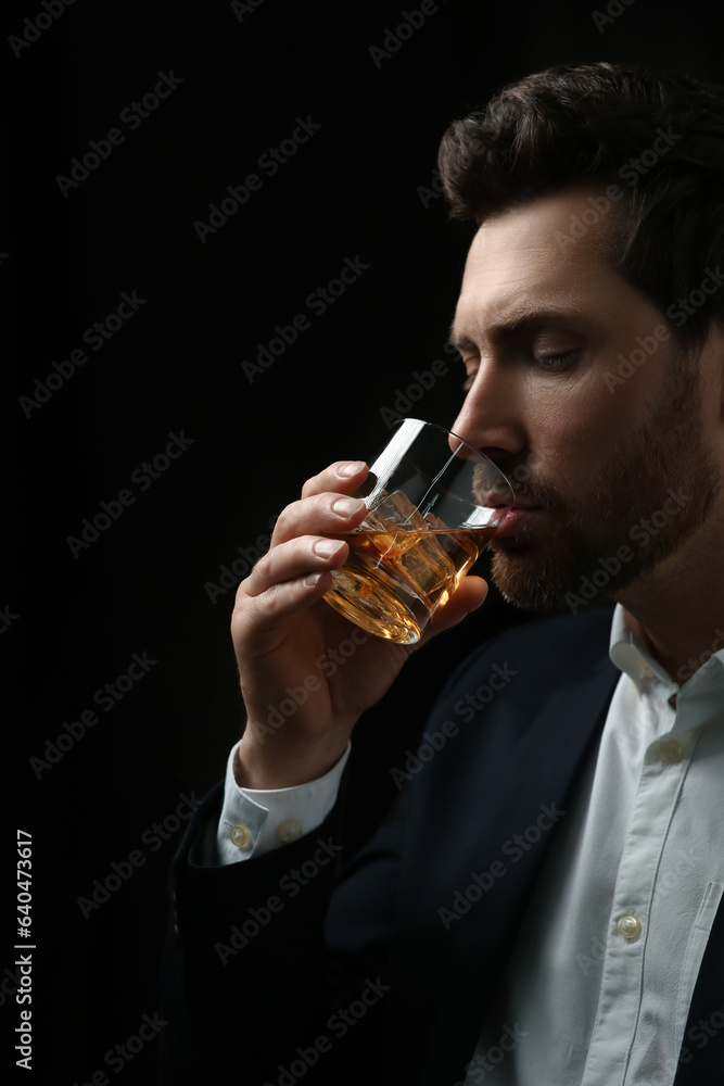 Man in suit drinking whiskey on black background Man in suit drinking whiskey on black background