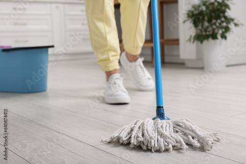 Woman cleaning floor with mop indoors, selective focus