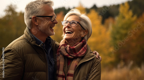 an American senior couple in their early 60s having a great time in there retirement years during the autumn season, pine trees in the background.