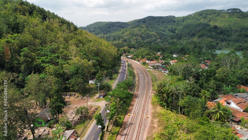 Aerial drone view of highway and railroad tracks among green trees and mountains Aerial drone view of highway and railroad tracks among green trees and mountains