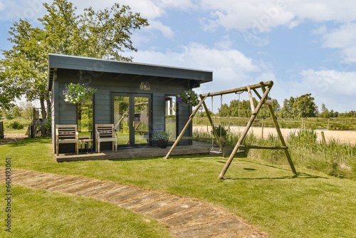 an outdoor play area with swings and swings in the grass, surrounded by blue sky and white fluffy clouds