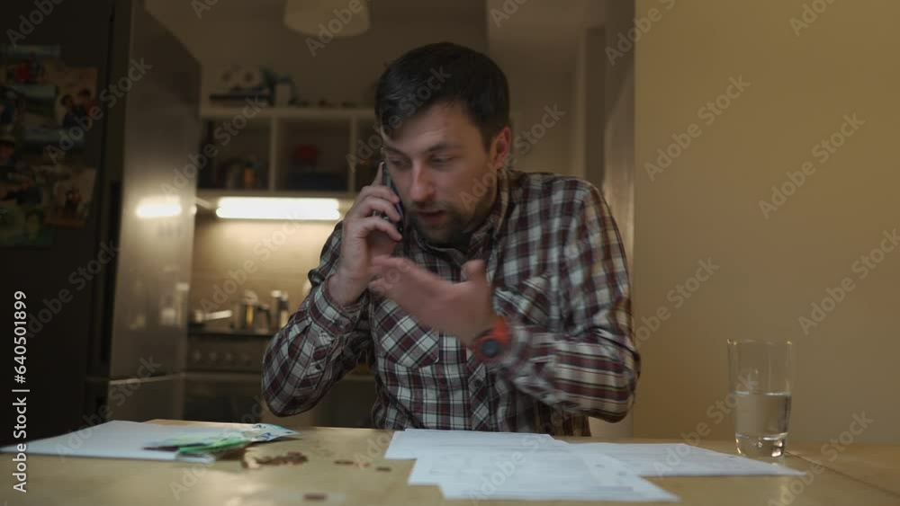 Querying an invoice. Tax troubles. Angry man emotionally discusses expenses over phone with insurance company at home in kitchen in evening. Financial problems, higher prices for electricity and fuel Querying an invoice. Tax troubles. Angry man emotionally discusses expenses over phone with insurance company at home in kitchen in evening. Financial problems, higher prices for electricity and fuel