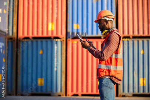 African factory worker or engineer using tablet computer and checking work in containers warehouse storage