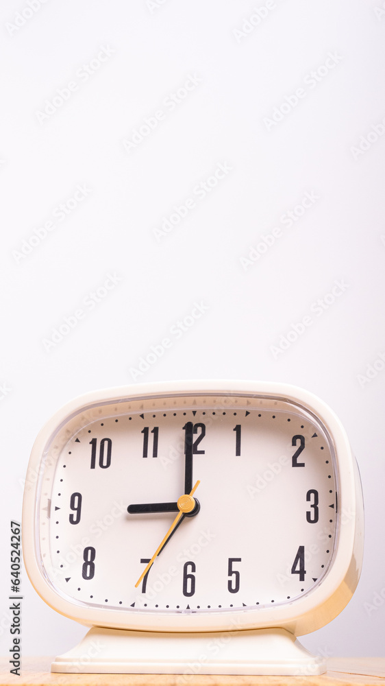 Vertical front view CU White alarm clock sits on the table. Vertical front view CU White alarm clock sits on the table.