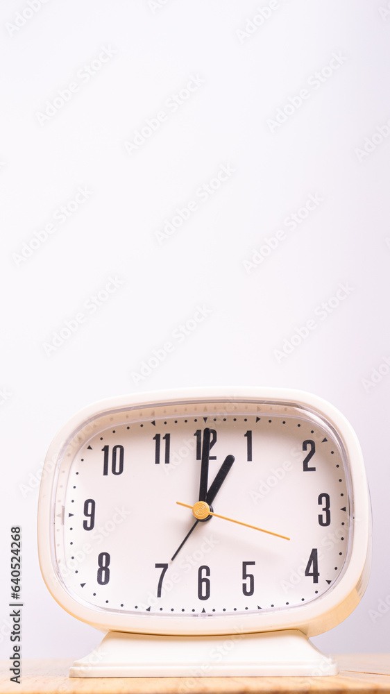 Vertical front view CU White alarm clock sits on the table. Vertical front view CU White alarm clock sits on the table.